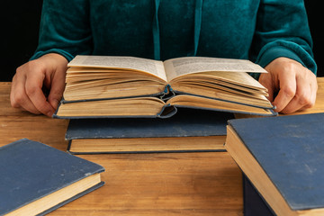 Female hands hold a book on a wooden table background.