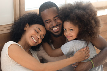 Happy african American couple with child embrace at home - Powered by Adobe