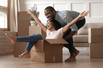 African happy wife sitting inside carton box husband rides her