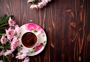 cup of coffee with flowers on wooden background