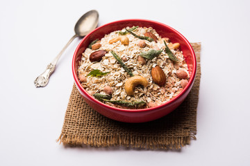 Oats Chivda / Chiwda is a healthy indian recipe with added chilli, peanuts, cashew, almond and curry leaf for flavour. Selective focus