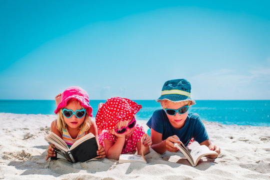 cute happy kids -boy and girls- read books on beach, family vacation