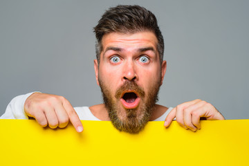 Man showing blank board with copy space. Advertisement. Surprised man holds empty placard....