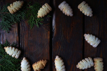 Christmas cookies and twigs of thuja on a dark wooden table