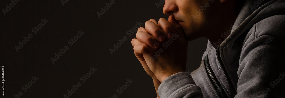 Wall mural religious young man praying to god on dark background, black and white effect - Wall murals