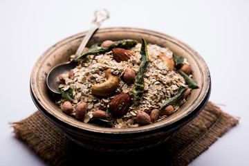 Oats Chivda / Chiwda is a healthy indian recipe with added chilli, peanuts, cashew, almond and curry leaf for flavour. Selective focus