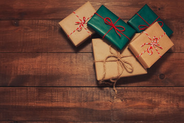 Pile of Christmas gifts on brown wooden table. Christmas rustic background. New Year, winter holiday, copy space, top view, present boxes