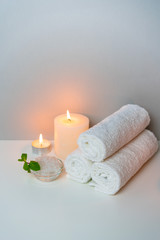 Obraz na płótnie Canvas SPA procedure at salon vertical concept photo on grey background with stack of white towels, candles and cup of sea salt.