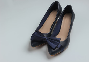 Minimalistic fashion still life. Women's high heel shoes and bow tie on white background.