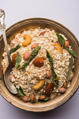 Oats Chivda / Chiwda is a healthy indian recipe with added chilli, peanuts, cashew, almond and curry leaf for flavour. Selective focus