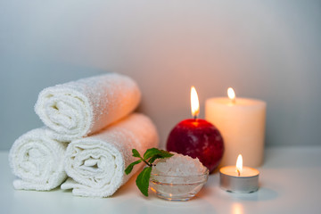 Obraz na płótnie Canvas SPA day concept photo with candle lights, stack of towels and sea salt in a cup.