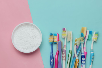 Lot of old toothbrushes, tooth powder on a blue-pink pastel background, top view, minimalism