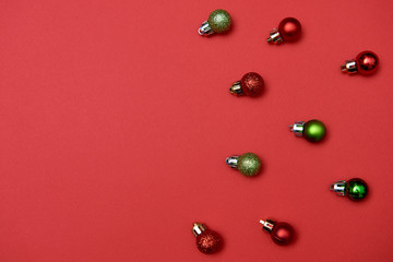 Creative Christmas pattern with red and green shiny baubles on red background, copy space. Minimal, winter, new year concept. Top view, flat lay
