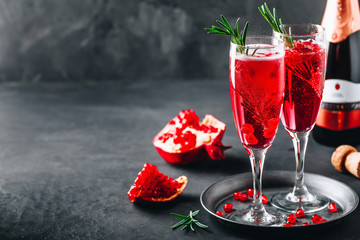 Pomegranate Champagne Cocktail with rosemary on gray concrete stone background