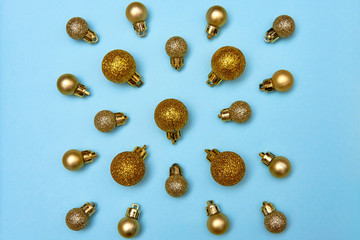 Creative Christmas pattern with golden shiny baubles on blue pastel background, copy space. Minimal, winter, new year concept. Top view, flat lay