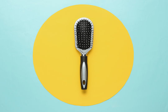 Stylish hairbrush on blue background with yellow circle. Women's Hair Care Accessories.