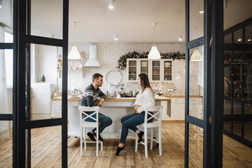 Loving couple sit in the New Year's kitchen waiting for the birth of their child