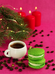 Green macaron with fondant on a red paper background. Nearby is a cup of espresso, roasted coffee...