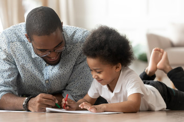 Caress father drawing with son family lying on warm floor