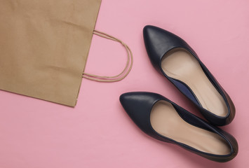 Shopping concept. Fashion studio shot. Women's high-heeled shoes and paper bag for shopping on pink pastel background. Top view