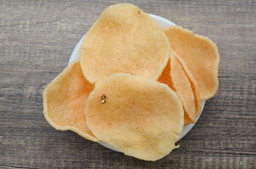 Crunchy shrimp rice cracker on white dish on wood background.