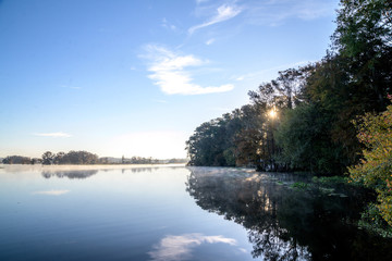 Fototapeta na wymiar Misty Morning Lake with Autumn Colored Trees and Foliage