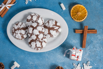 Delicious marble cookies strewn with icing sugar. New Year's gingerbread cookie on a blue background with cinnamon, snowflakes and marshmallows. Homemade festive baking for the New Year and Christmas.