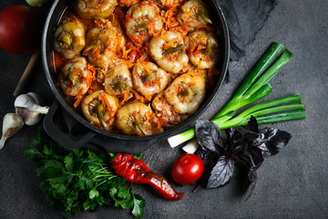 Stuffed peppers with rice, meat and spices in a dark pan on a dark background top view.