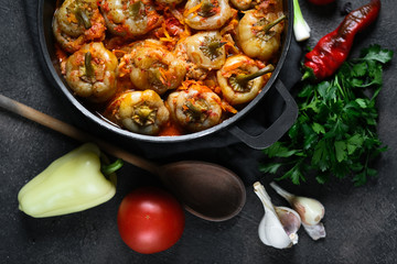 Stuffed peppers with rice, meat and spices in a dark pan on a dark background top view.