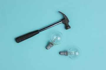 Hammer and old light bulbs on a blue background. Top view