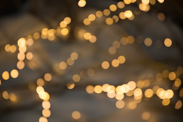Christmas garlands with blurred focus in the form of bokeh and Golden misty haze on a dark background. Abstract colorful background with Golden bokeh.