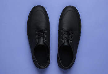 Men's leather black shoes on a purple background. Top view