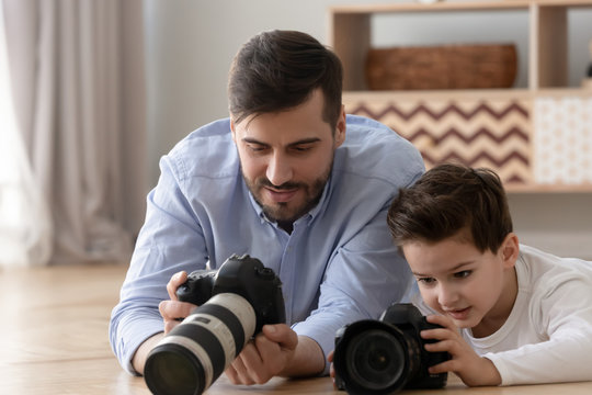 Caring father teaching cute little son to use digital camera