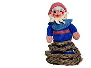 A hand made elf with red cap and beard standing on a rack made of tree roots. Gnome isolated