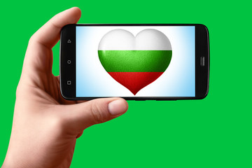 Bulgaria flag in the shape of a heart on the phone screen. Smartphone in hand shows the heart of...