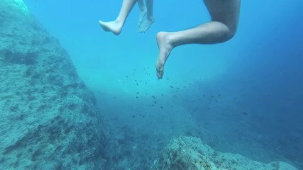 underwater shot in the blue clear sea. People in deep water move their arms and legs to stay on the surface, slow motion. Sea Vacation Concept