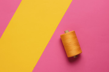 Orange skeins of thread on a pink-yellow pastel background. Top view