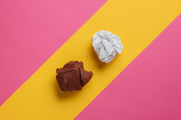 crumpled balls of paper on a yellow-pink pastel background. Top view