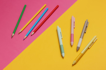 A lot of colored pens and pencils. close-up on yellow pink background.