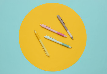 A lot of colored pens close-up on blue background with yellow circle.