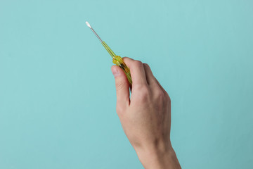 Repair concept. Female hand holds a screwdriver on a blue studio background. - obrazy, fototapety, plakaty