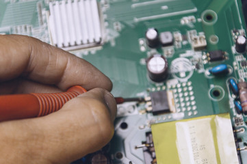 Technician repairing television board ,engineer measures the voltage on the television board