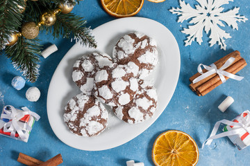 Delicious marble cookies strewn with icing sugar. New Year's gingerbread cookie on a blue background with cinnamon, snowflakes and marshmallows. Homemade festive baking for the New Year and Christmas.