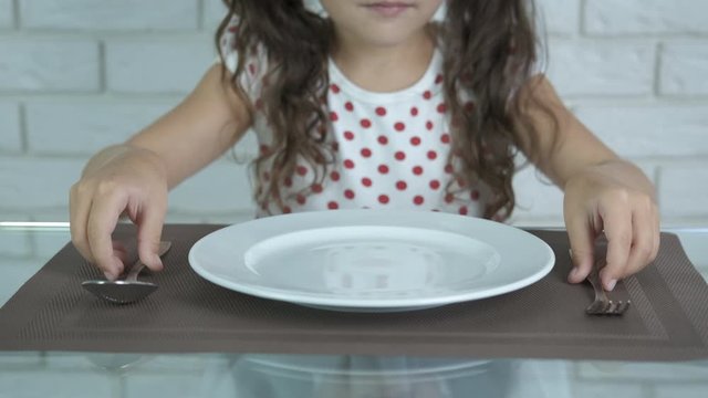 The child at the table with an empty plate.