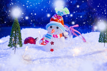 Snowman with Christmas balls on snow over fir-tree, night sky and moon. Shallow depth of field....