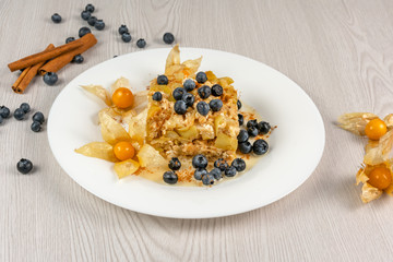 Baked apple slices with cottage cheese on a white plate on the table