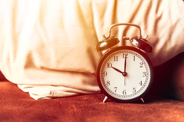 Alarm clock on the bed at the pillow for sleeping times wake up timer concept.