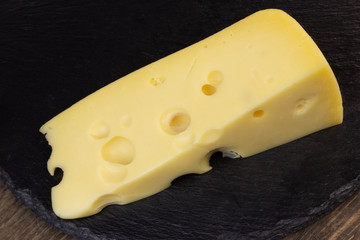 Still life of Swiss type cheese on a rustic stone background.