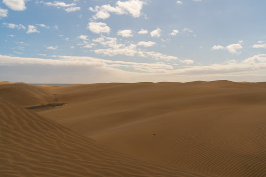 Amazing sand dunes during sunny and windy day in the Natural Reserve of Dunes of Maspaloma in Gran Canaria with sand dust and ocean in background, Canary Islands, Spain © Marcin