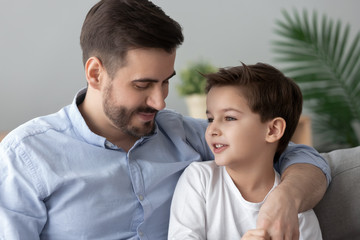 Loving father hugging, talking with little son, spending time together